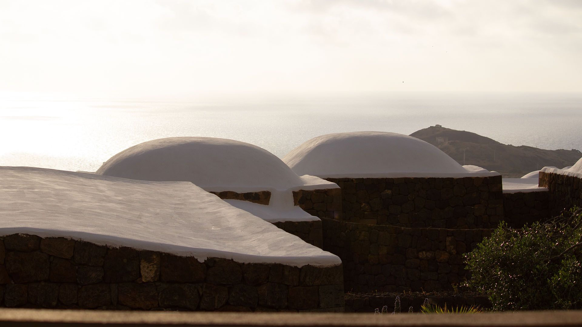 Caratteristici tetti a cupola bianchi dei dammusi di Pantelleria con vista sul mare al tramonto o all'alba.