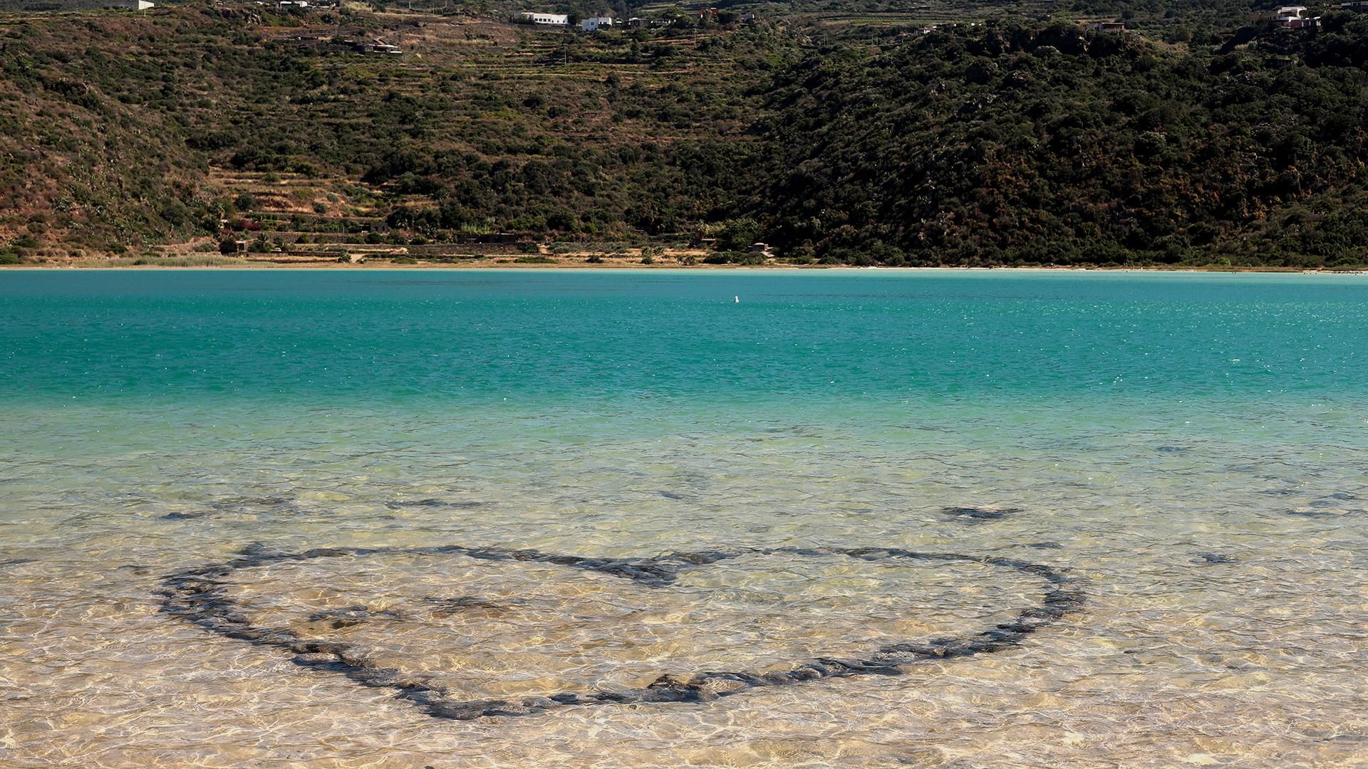 Cuore disegnato con pietre vulcaniche nei fondali trasparenti del Lago di Venere, immerso nella natura rigogliosa di Pantelleria.